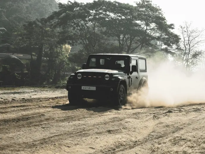 A black jeep driving down a dirt road